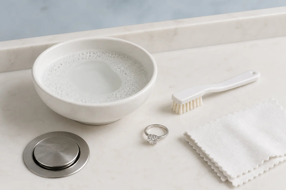 Moissanite ring beside lukewarm soapy water, a very soft brush and a lint-free cloth